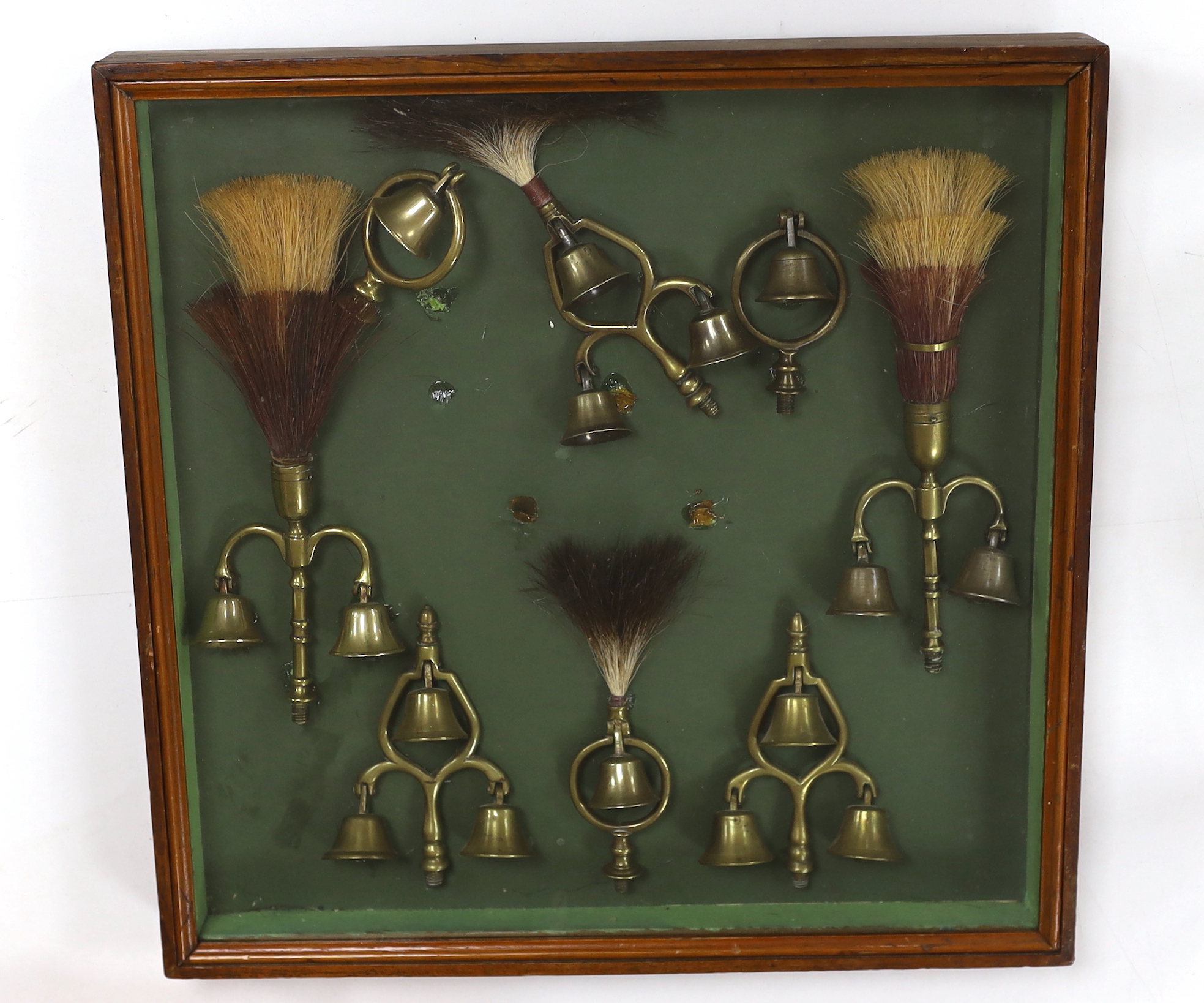 A collection of Victorian horse brass bell terrets, housed in a display case, 46cm high